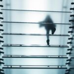 Una persona camina por una escalera de cristal